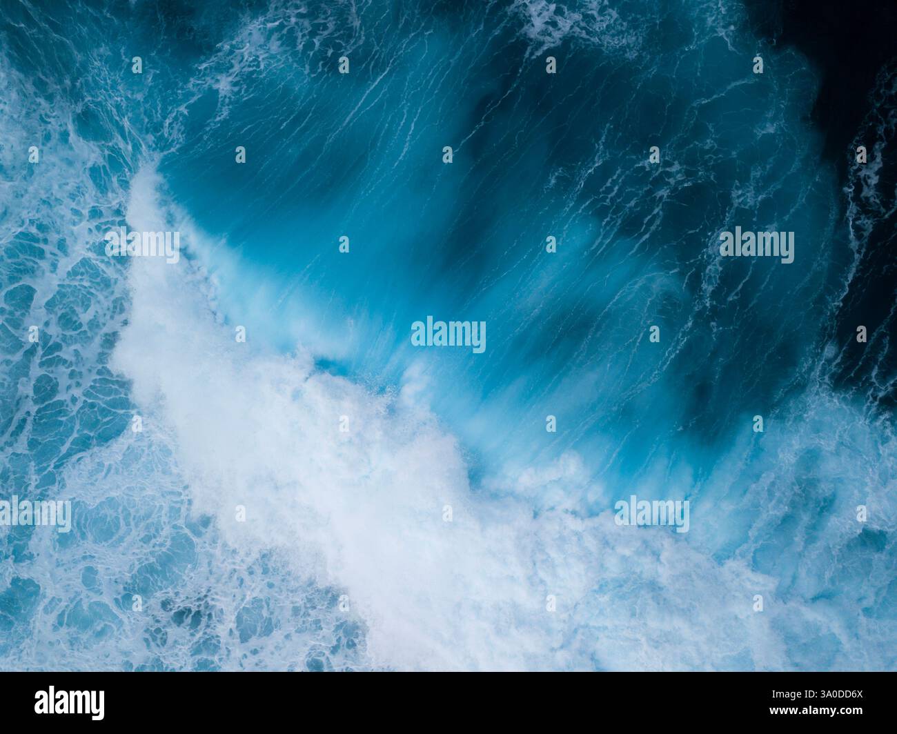 Vista aerea astratta di onde turbolente che si infrangono con sfumature blu e verdi delle acque tropicali dell'oceano Foto Stock