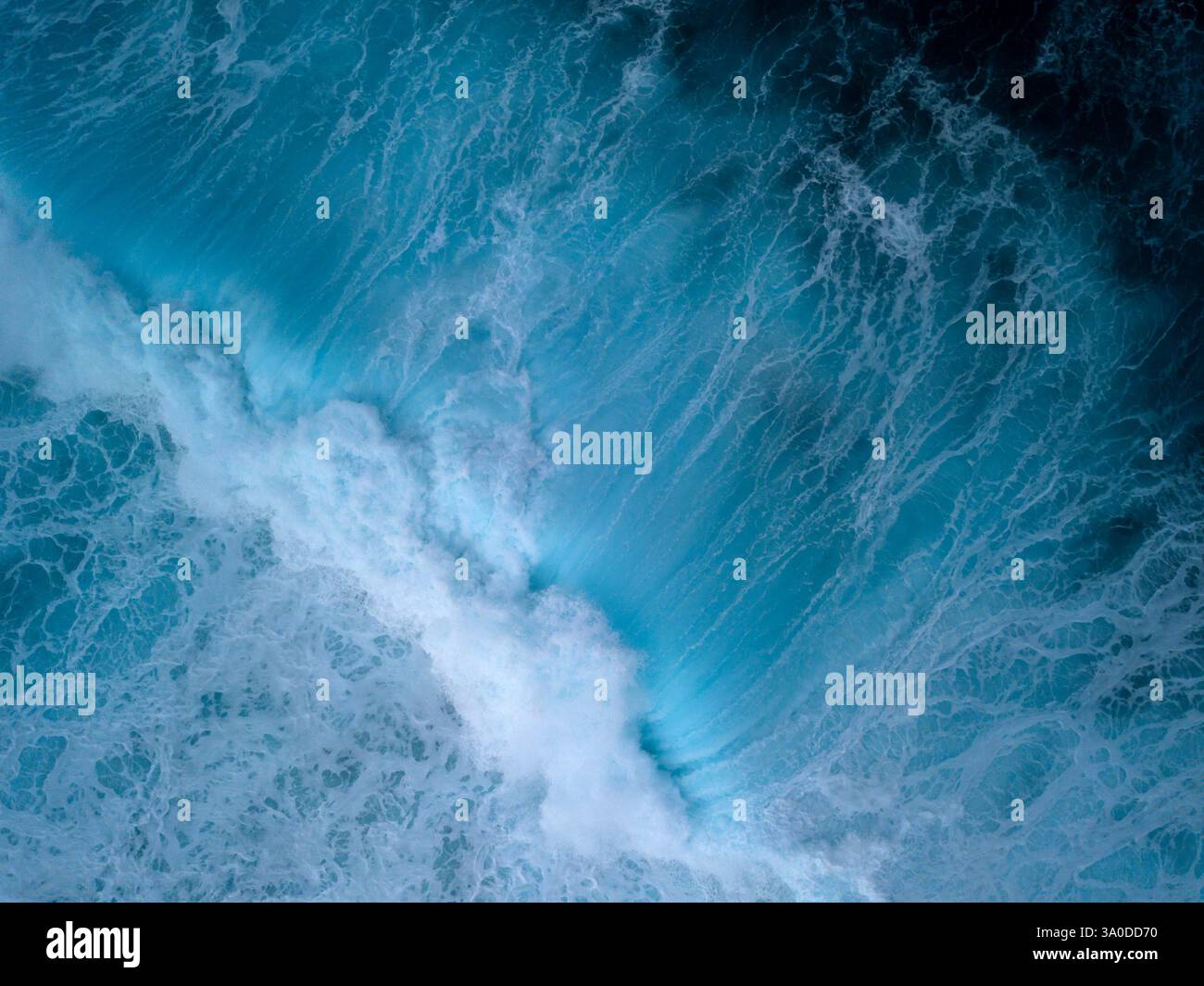 Vista aerea astratta di onde turbolente che si infrangono con sfumature blu e verdi delle acque tropicali dell'oceano Foto Stock