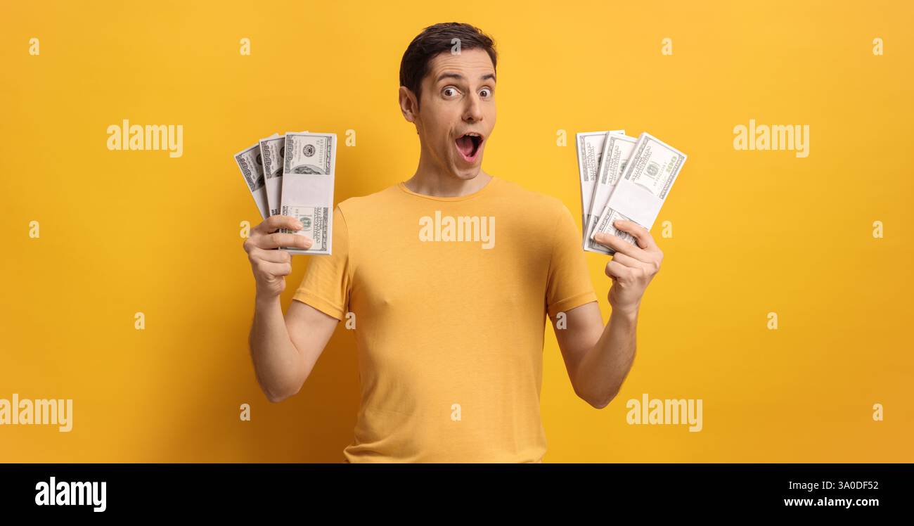 Giovane felice con soldi in mano su sfondo giallo Foto Stock