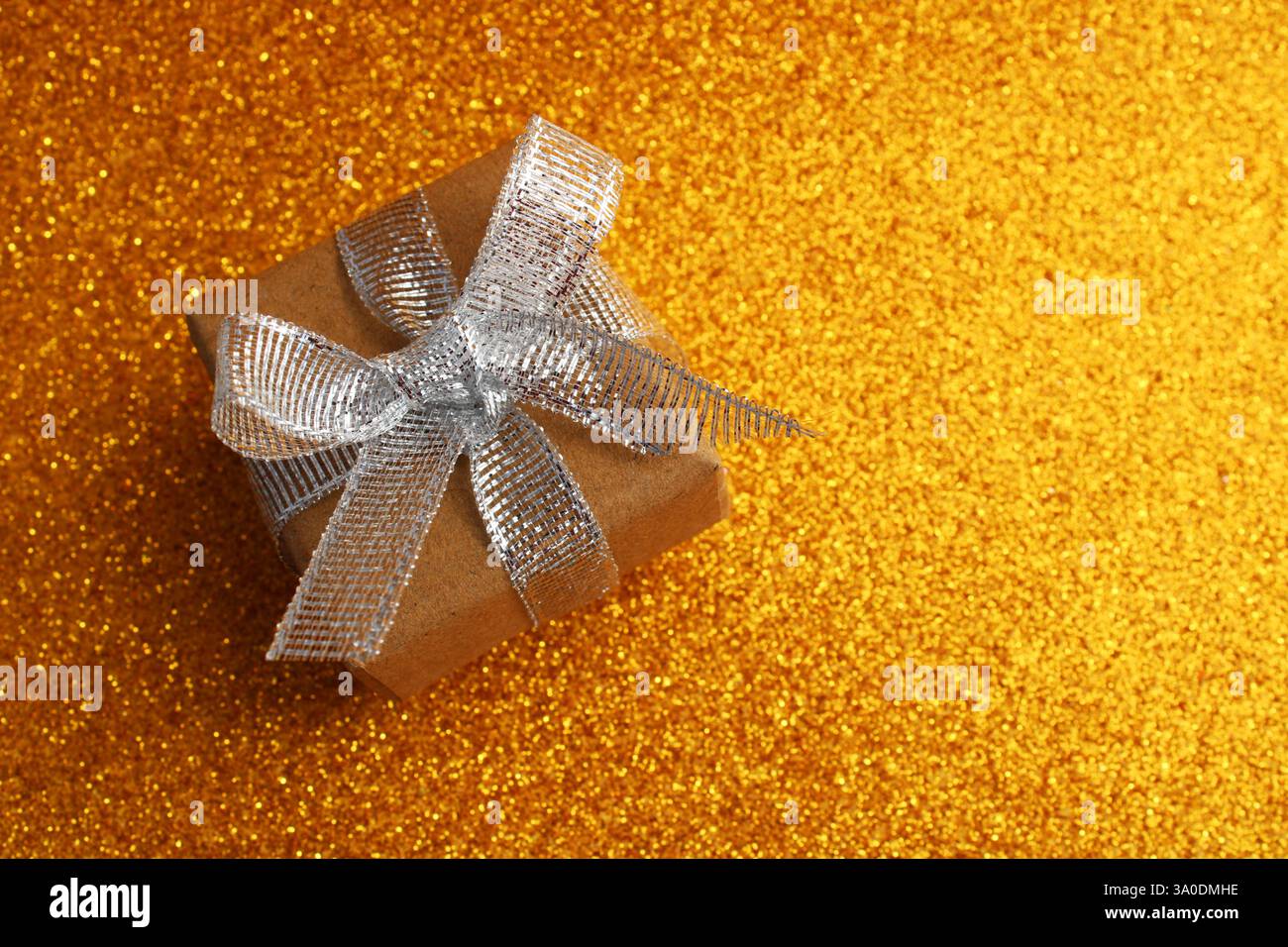Confezione regalo con fiocco a nastro color argento glitter su sfondo oro Foto Stock