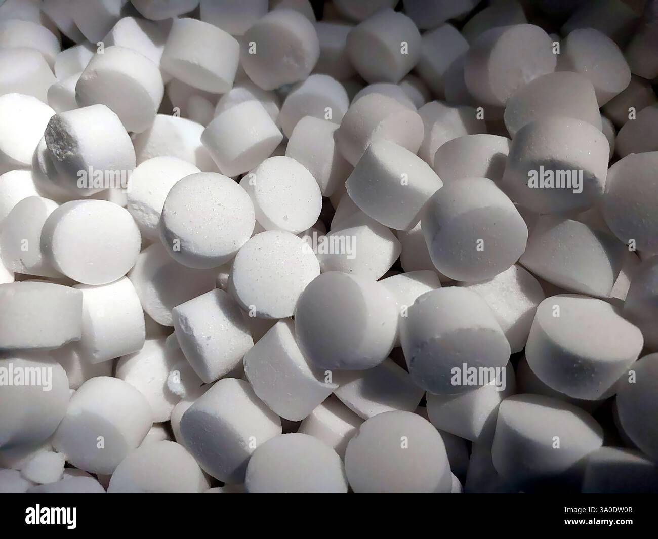 Il sale per tavoletta si appoggia su una pila, mostrando la sua forma arrotondata e il colore bianco puro. Perfetto per esaltare i sapori, questo essenziale culinario viene utilizzato in vario Foto Stock