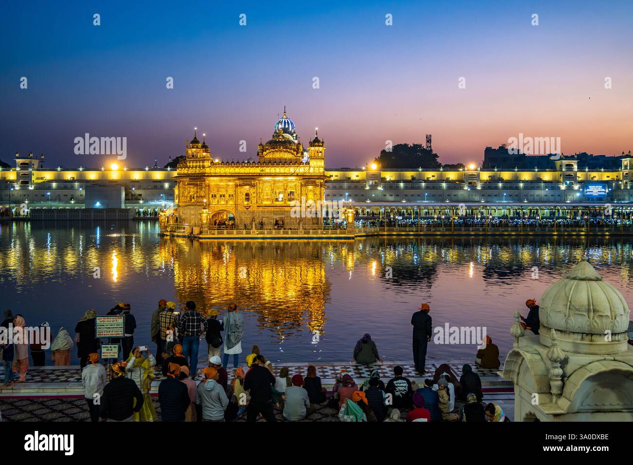 Visitatori e adoratori al Tempio d'Oro, o Harmandir Sāhib, ammirando tutta la sua gloria con il cielo colorato al crepuscolo. Amritsar, Punjab, India. Foto Stock Visitatori e adoratori al Tempio d'Oro, o Harmandir Sāhib, ammirando tutta la sua gloria con il cielo colorato al crepuscolo. Amritsar, Punjab, India. Foto Stock
