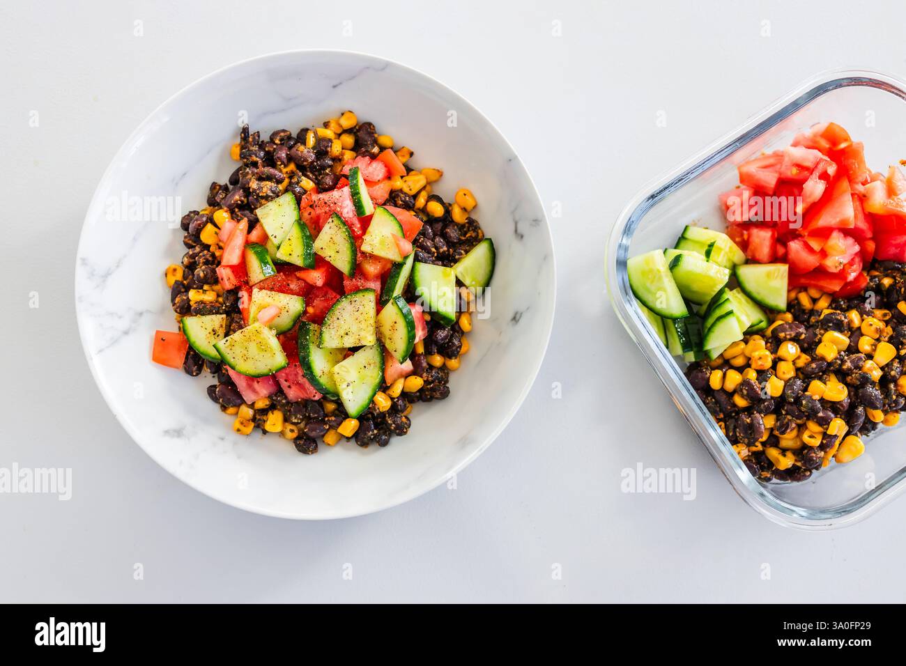 insalata di pomodoro e cetrioli di mais, servita in una ciotola e un contenitore per il pranzo, ricette salutari Foto Stock insalata di pomodoro e cetrioli di mais, servita in una ciotola e un contenitore per il pranzo, ricette salutari Foto Stock