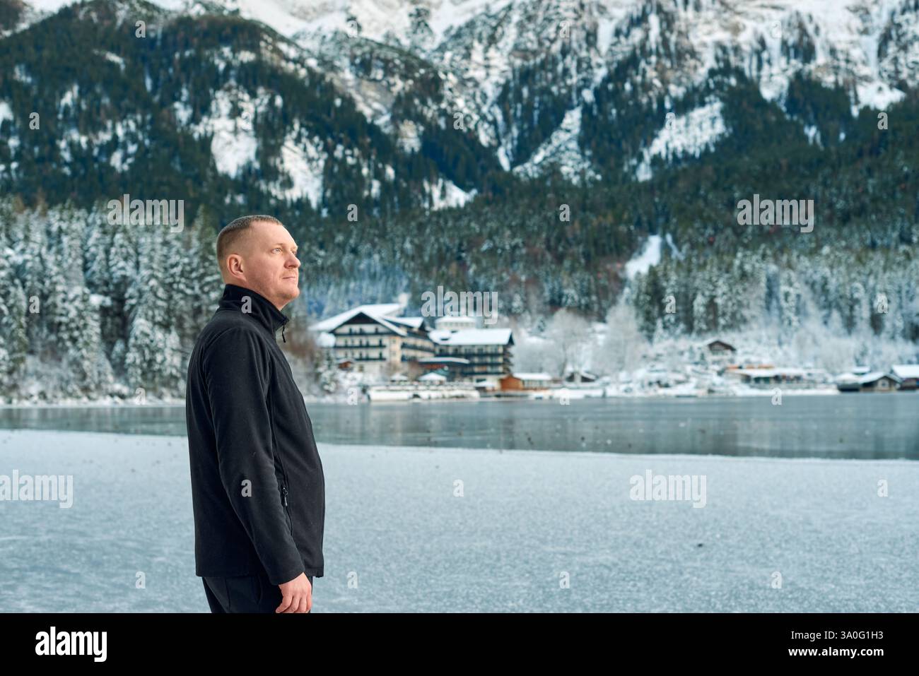 Questa fotografia ad alta risoluzione cattura un tranquillo paesaggio invernale in una regione montuosa, con un uomo di mezza età come soggetto centrale. La ma Foto Stock