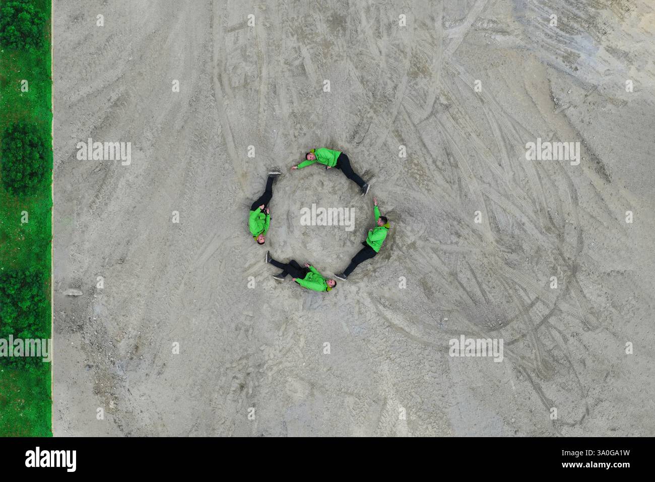 Layout creativo realizzato con un uomo in verde che forma un globo su sfondo grigio. Fotografia aerea. Concetto minimale Earth Day. Foto Stock