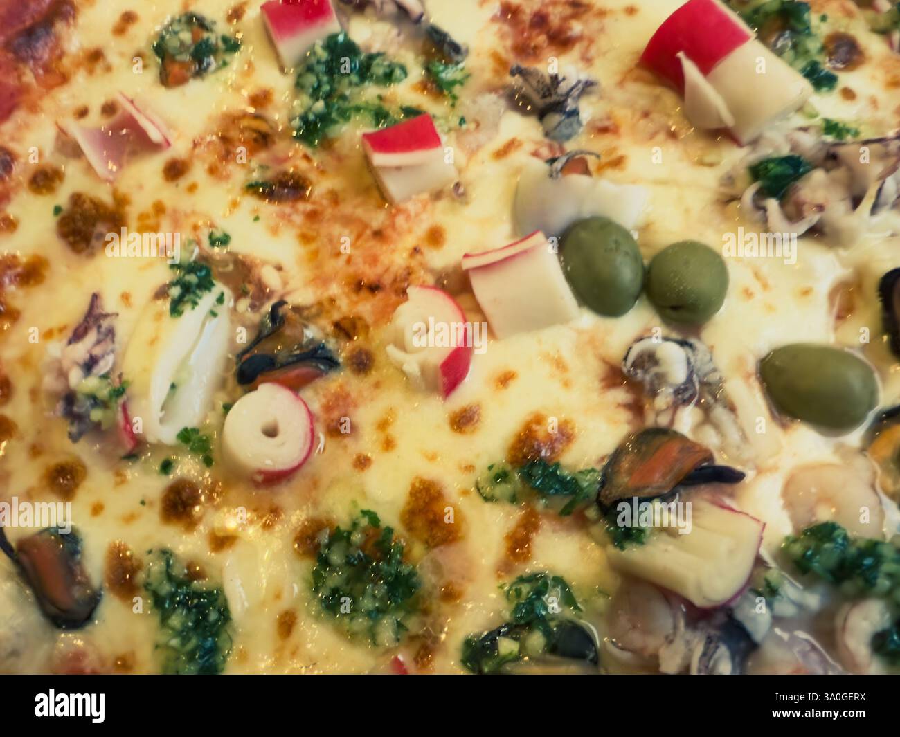 Pizza a base di pesce con bastoncini di granchio, olive verdi e formaggio fuso - primo piano Foto Stock