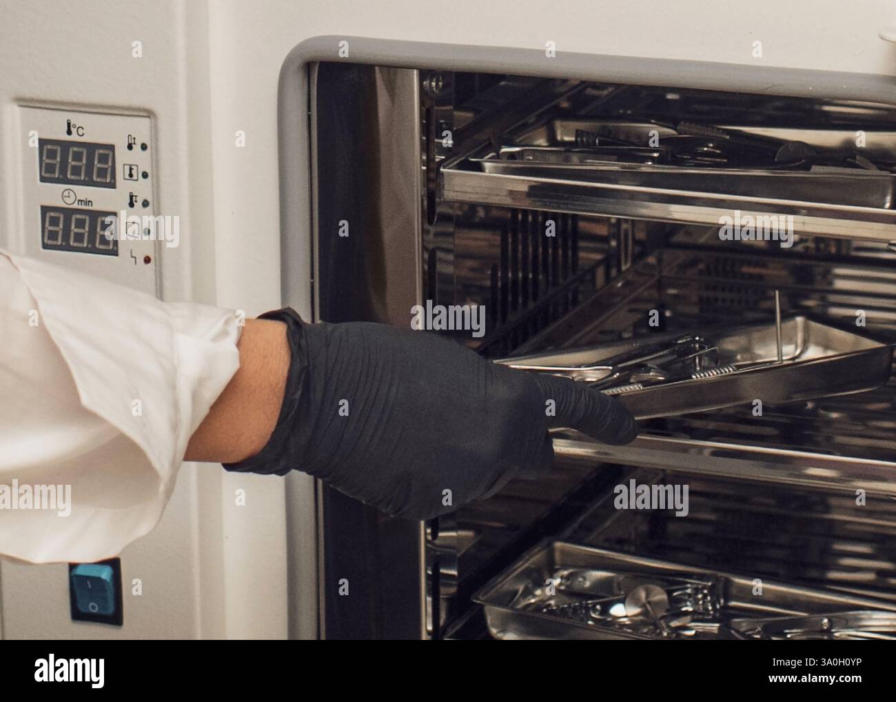 Uno specialista in guanti carica strumenti per manicure e pedicure in uno sterilizzatore. Igiene e sicurezza durante le procedure cosmetiche Foto Stock