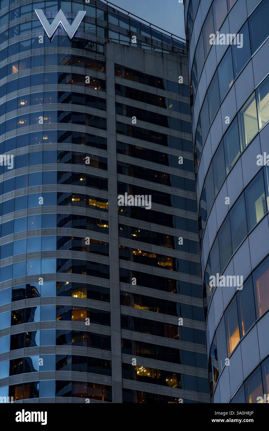 Questa elegante immagine serale mostra l'iconico W Hotel, un lussuoso grattacielo con il suo distintivo logo "W", adagiato contro il cielo crepuscolo di Bangkok, T. Foto Stock