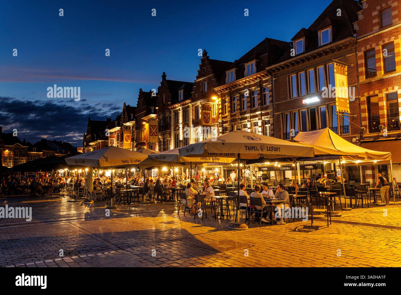 Gente che mangia e beve la sera nella Grand Place, piazza al tramonto, Tournai, Belgio Foto Stock
