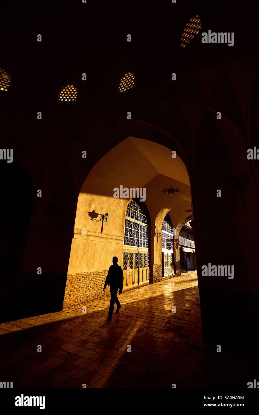 Vista della porta con luce dorata all'alba e silhouette nera dei turisti nella piazza della cultura di Bukhara, Uzbekistan Foto Stock