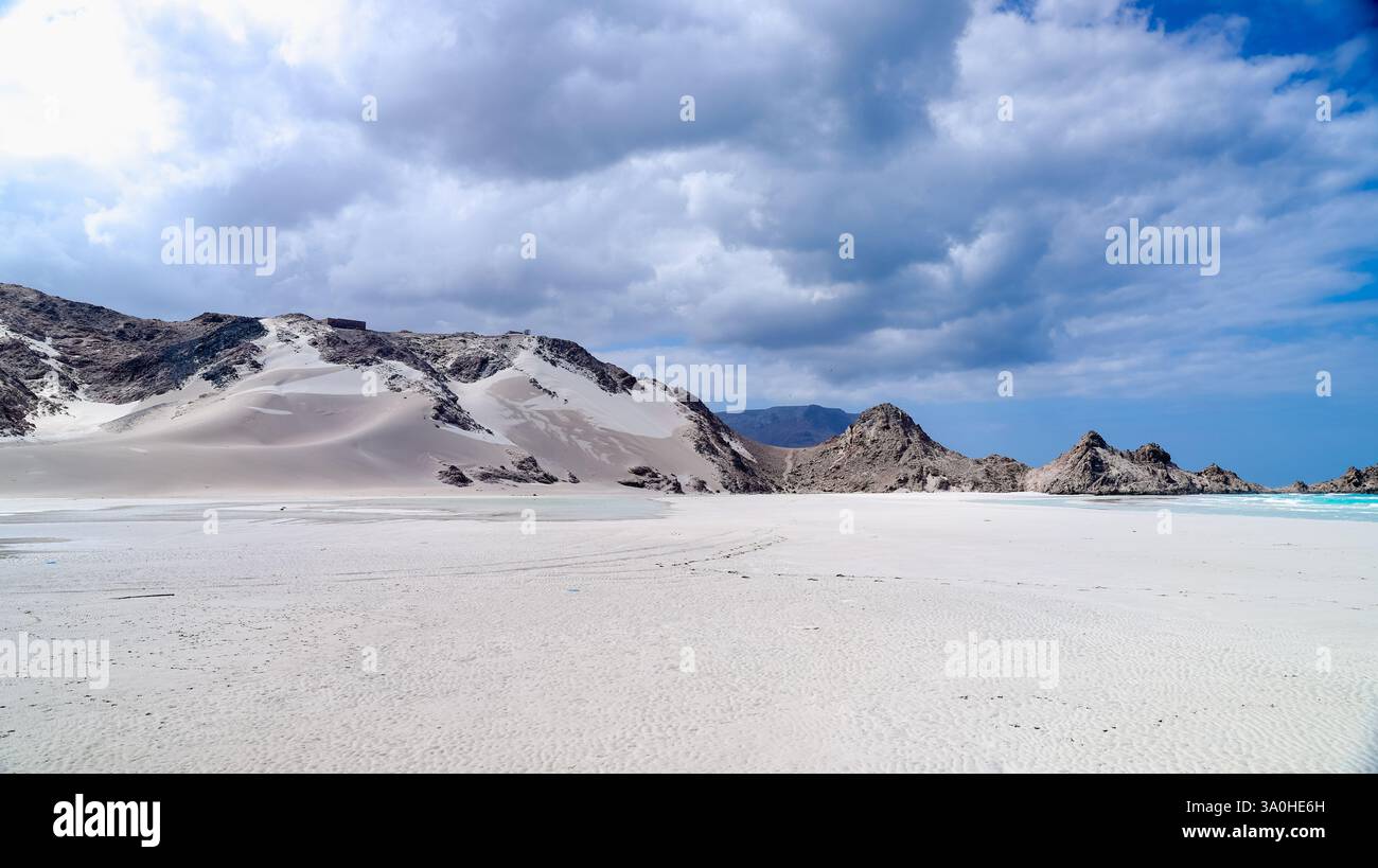 Una vista mozzafiato che cattura il paesaggio unico di Socotra caratterizzato da sabbia bianca, affioramenti rocciosi e un vasto cielo con nuvole. Foto Stock