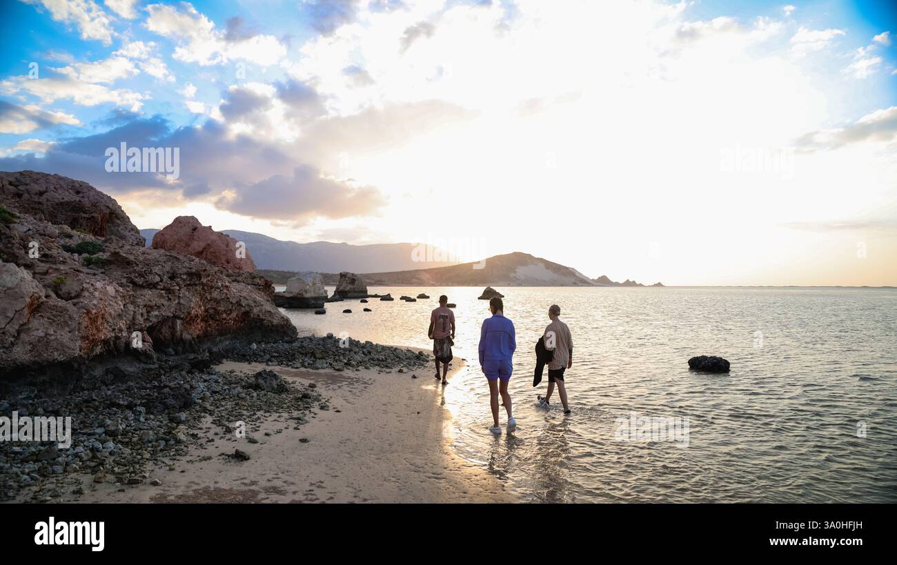 Gli individui camminano lungo la costa di Socotra, godendosi lo splendido tramonto e la bellezza naturale che li circonda. Foto Stock