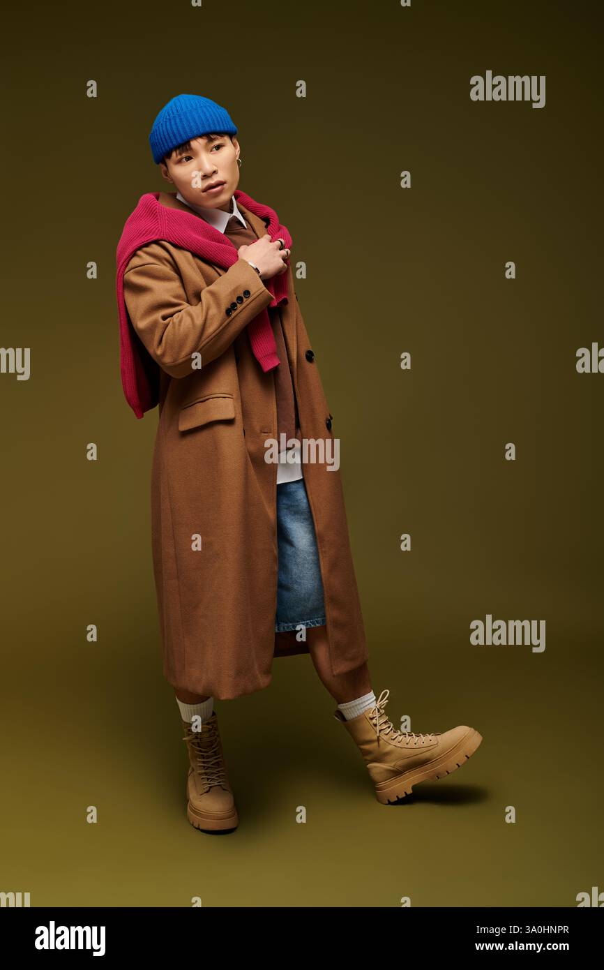 Un giovane uomo sicuro di sé sfoggia uno stile unico in un outfit alla moda e colori vivaci. Foto Stock