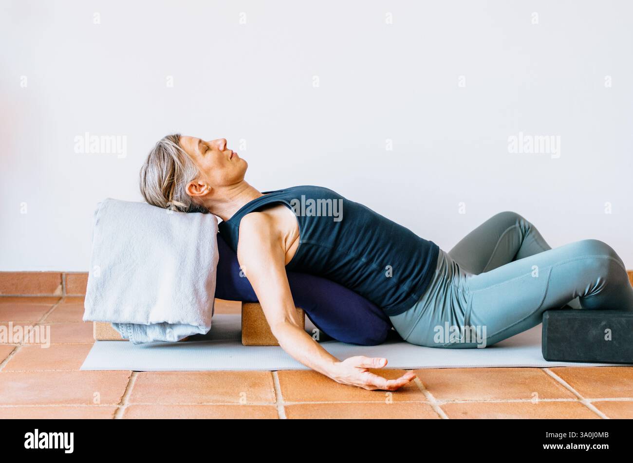 La donna che praticava ha sostenuto lo yoga rigenerante con oggetti di scena Foto Stock