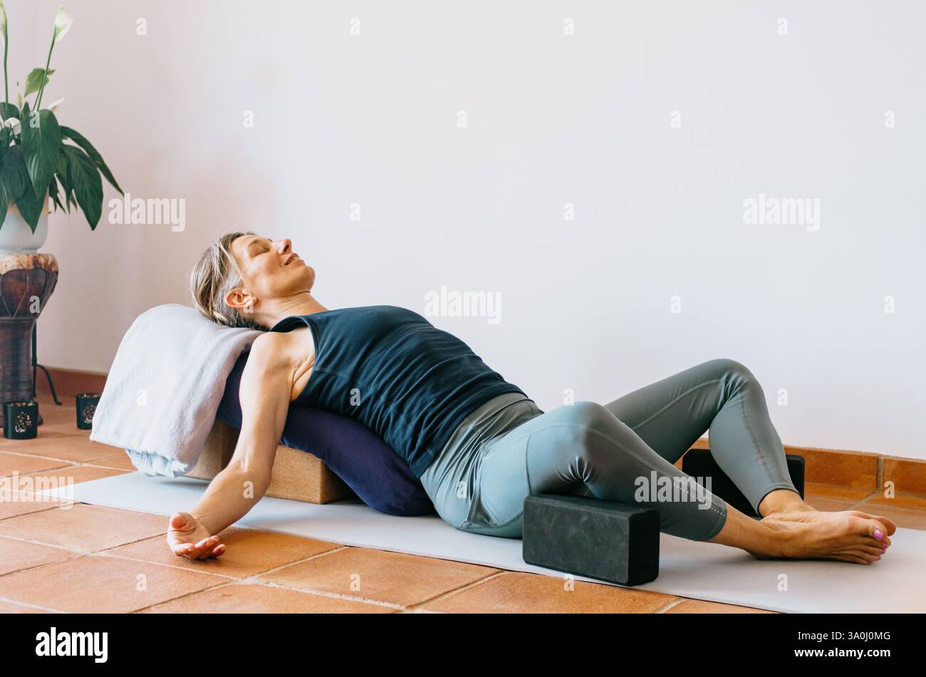 Donna che fa yoga rigenerante ha sostenuto la posa della farfalla con gli oggetti di scena Foto Stock