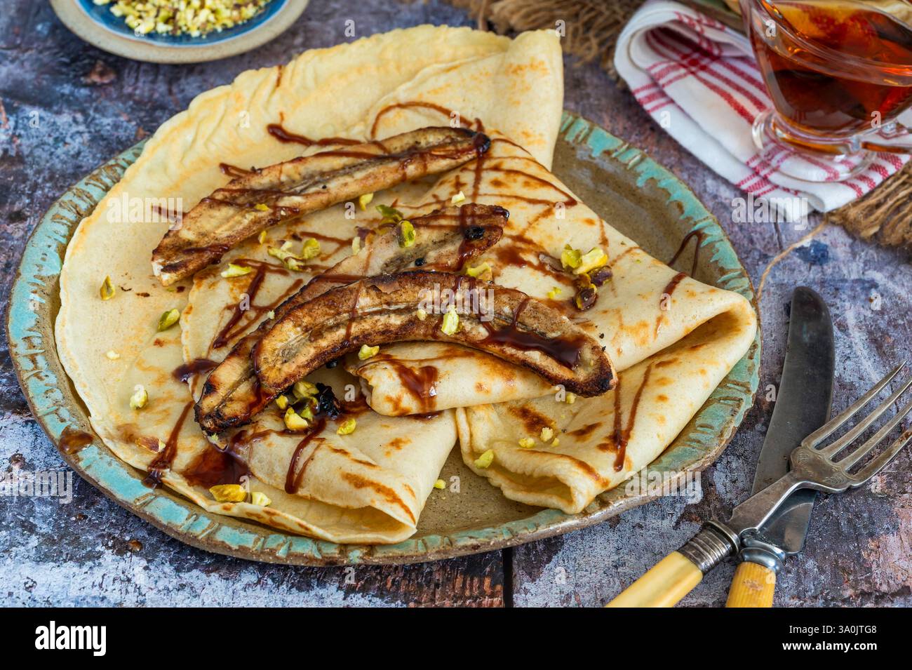 Crepe fatte in casa con banane caramellate e pistacchi schiacciati Foto Stock