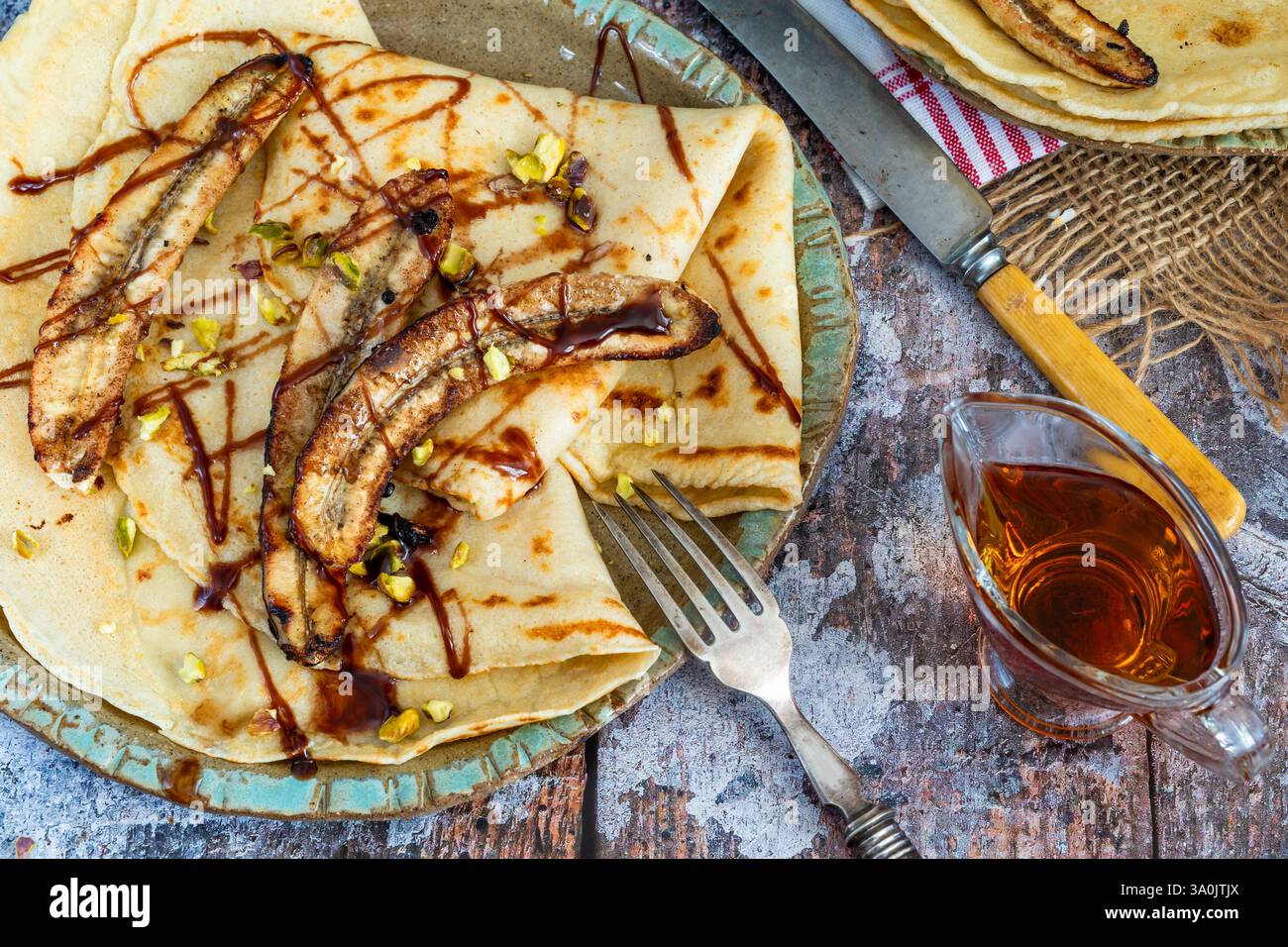 Crepe fatte in casa con banane caramellate e pistacchi schiacciati Foto Stock