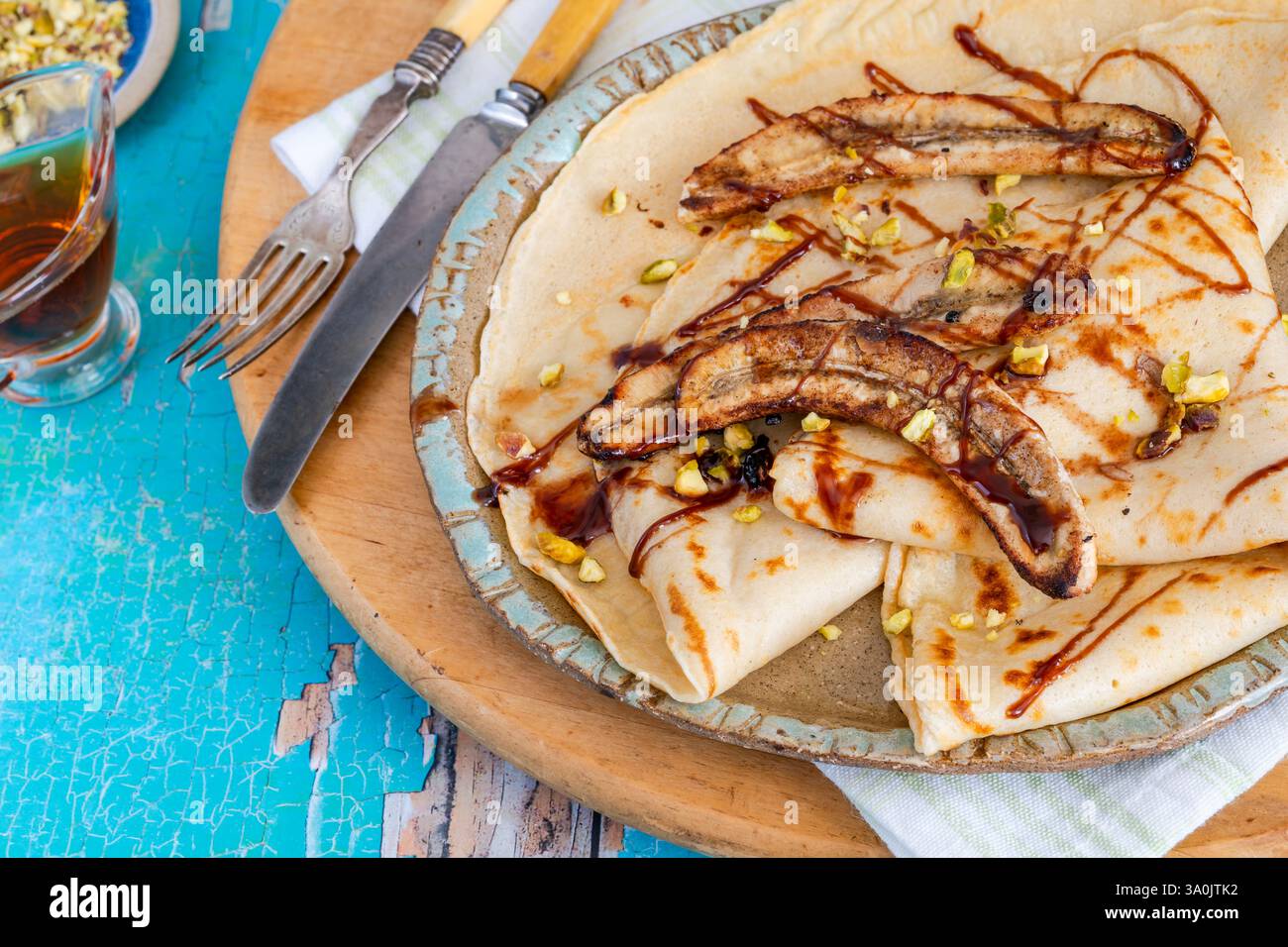 Crepe fatte in casa con banane caramellate e pistacchi schiacciati Foto Stock