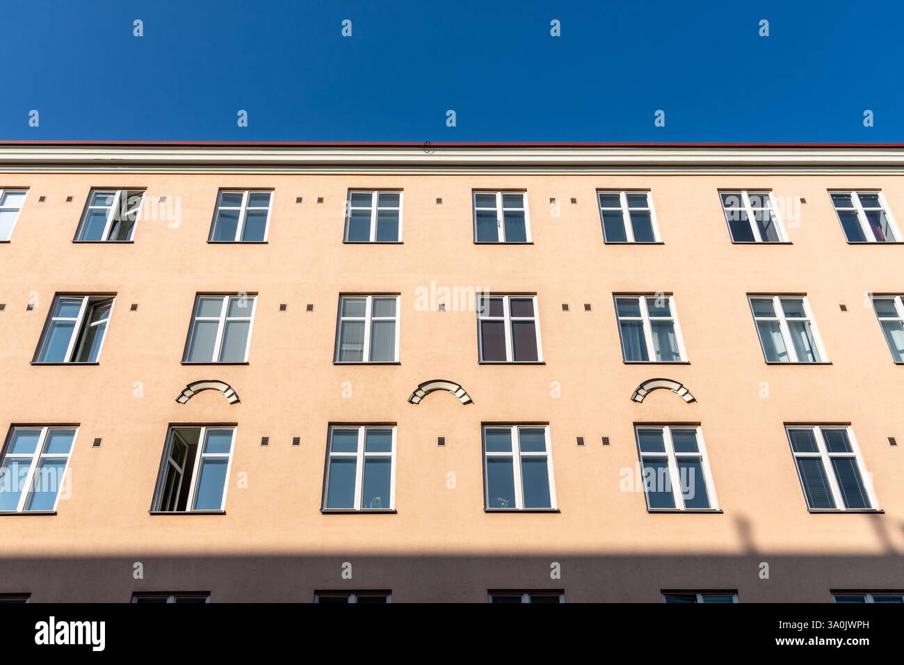 Un angolo verso l'alto mostra la facciata uniforme di un edificio Helsinki in una giornata luminosa con marrone chiaro e blu. Foto Stock