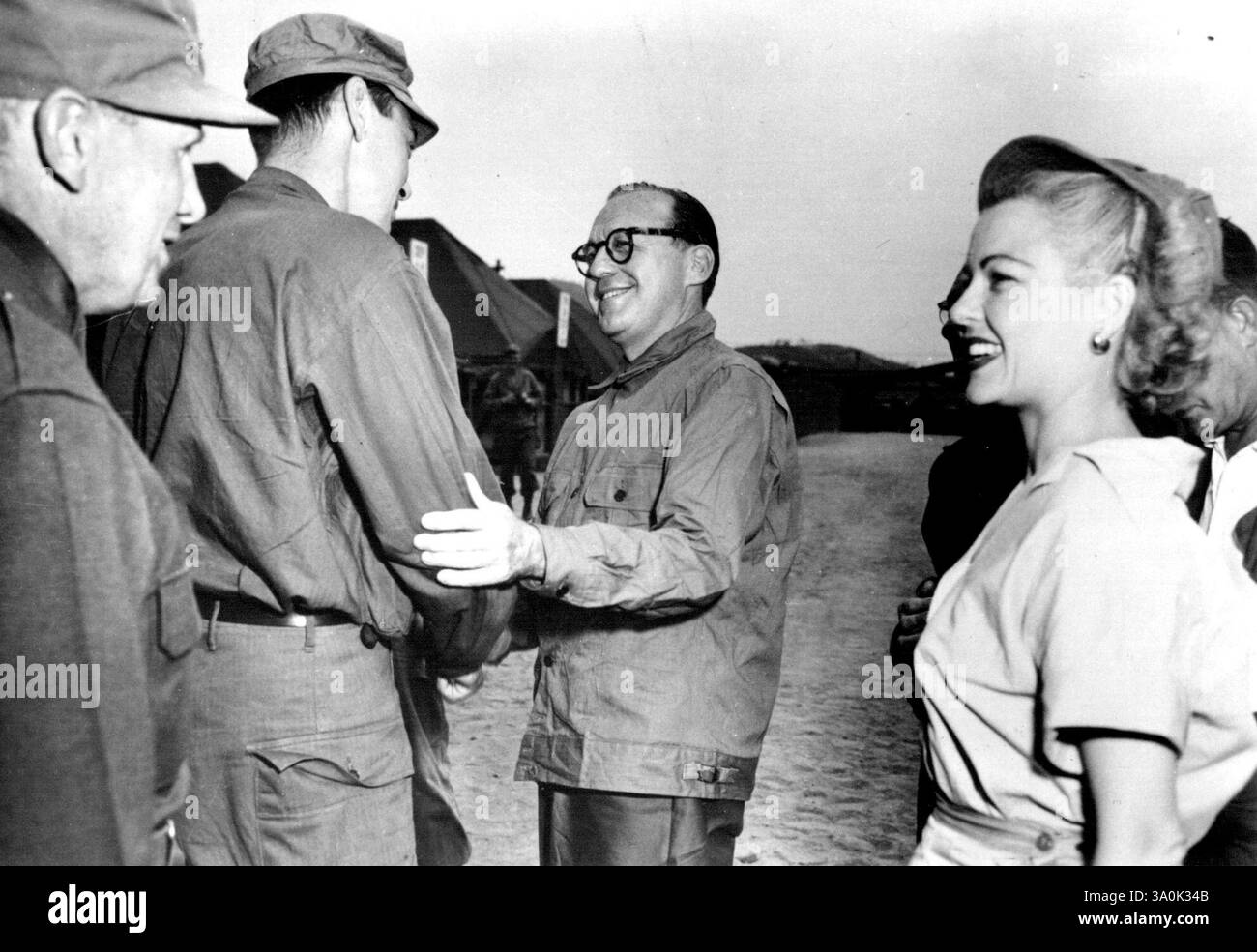 Mr. Alexander in Corea -- il sottosegretario dell'esercito Archibald Alexander (L-background) stringe la mano al comico Jack Benny che è in tour in Corea, mentre il tenente generale Edward M. Almond. (L-Foreground) parla con la star dello schermo Marjorie Reynolds. 4 luglio 1951. (Foto di J. Guzman, US Army Photo). Foto Stock
