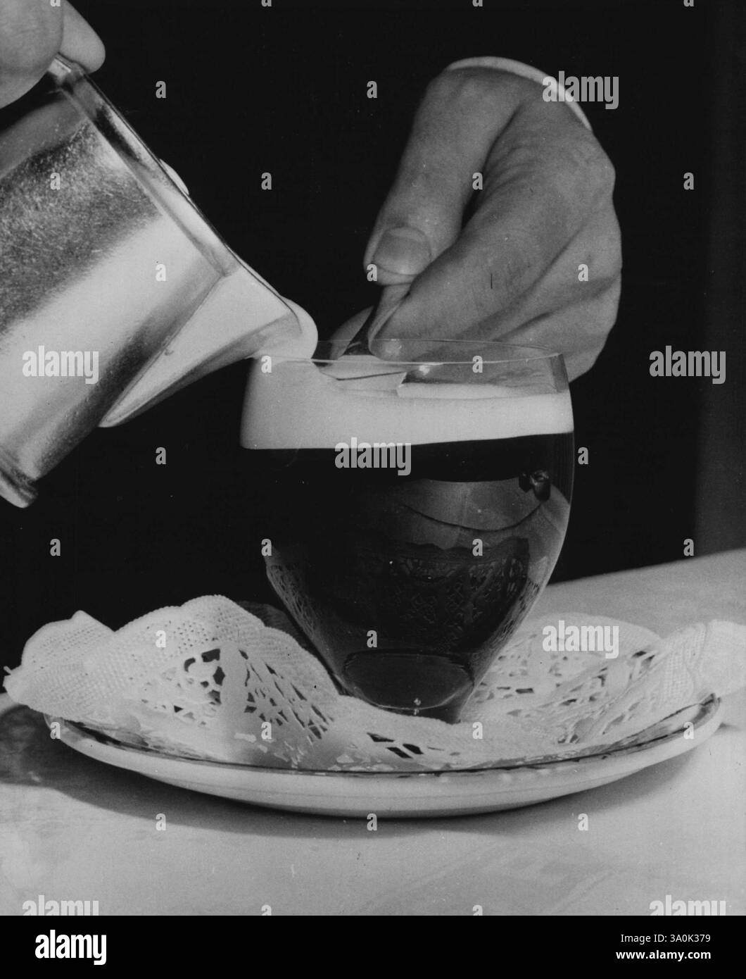 Tazza di caffè d'Europa: Sesto di undici -- l'ultimo passo per fare il "caffè gaelico" è la dipendenza da molta panna fresca, leggermente montata. Viene versato sulla parte superiore del caffè su un cucchiaio in modo che la panna rimanga intatta e galleggi. Nel bicchiere ci sono anche whisky irlandese e zucchero. Gli irlandesi lo adorano! 1° gennaio 1954. (Foto di United Press). Foto Stock