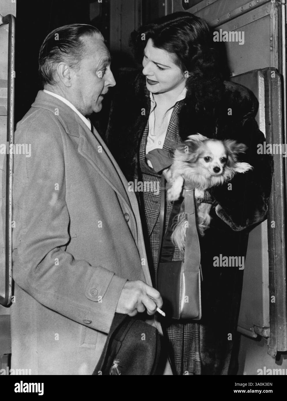 Interpretando il ruolo etero di padre, John Barrymore saluta sua figlia, Diana, come lei è arrivata ***** Los Angeles, California, per avere la possibilità di fare il suo debutto cinematografico. Il cane è un papiliano belga. 14 gennaio 1942. (Foto di Acme Photo). Foto Stock