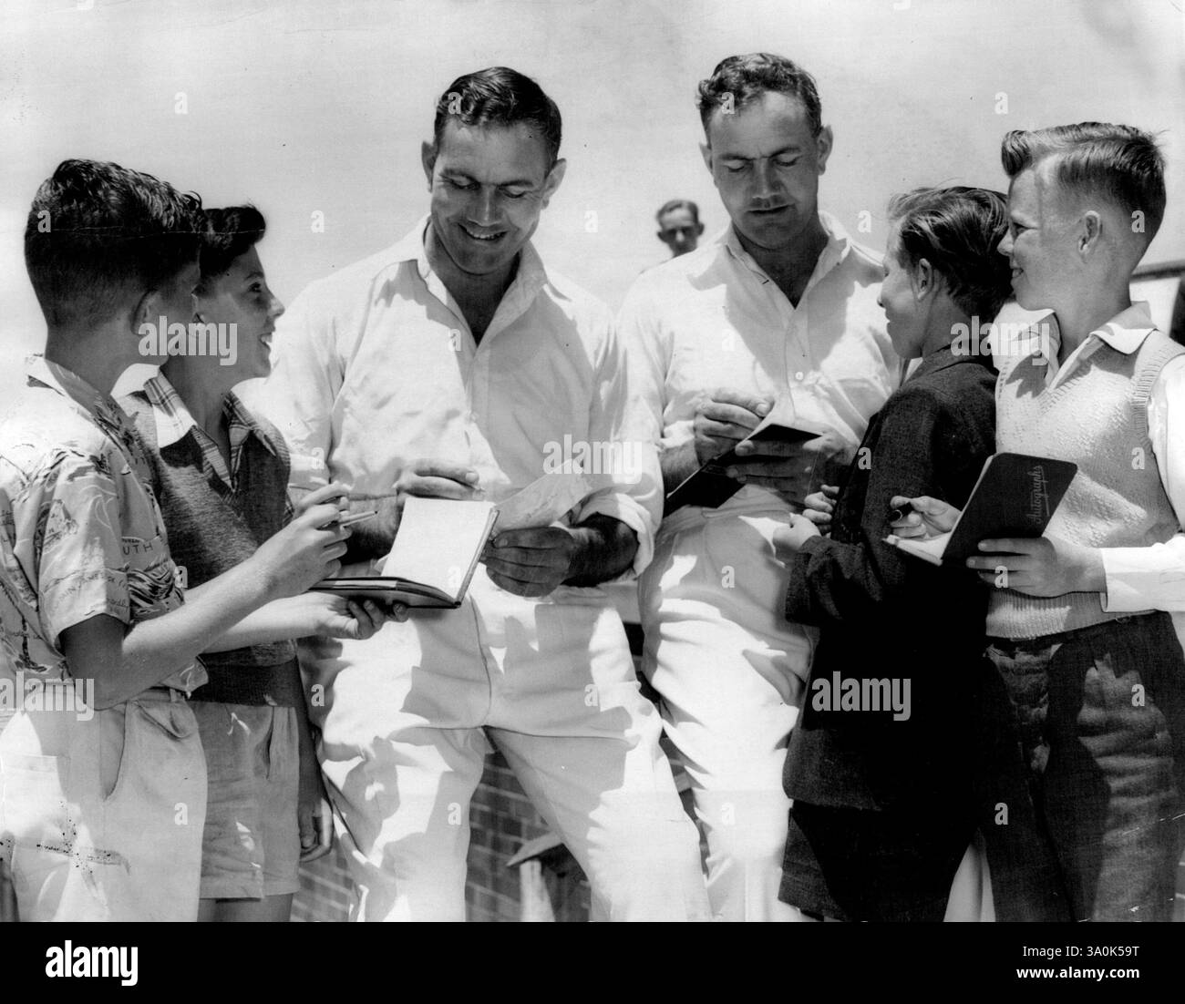 Il giocatore di cricket inglese Alec Bedser e suo fratello gemello Eric fanno parte di una partita di cricket Change Cricket al Waverey Oval, in attesa che firmino libri autografi per Peter Morris, Peter Wood, Ray Tooney, Michael McHale. 20 novembre 1955. (Foto di Martin James Brannan/Fairfax Media). Foto Stock