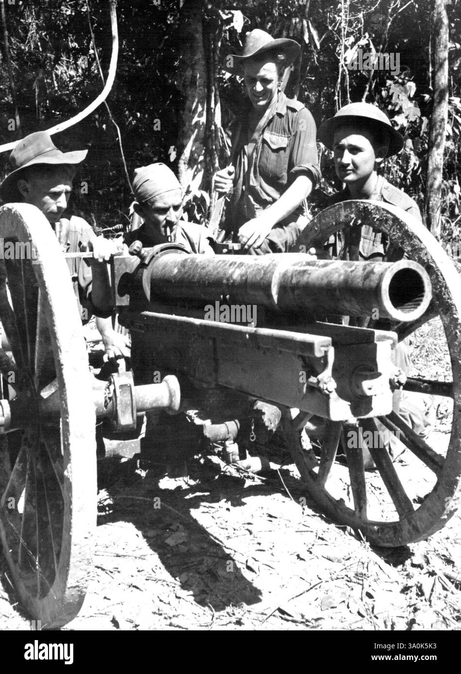 Fanti australiani su Tarakan con un cannone da 75 mm catturato dai giapponesi, il cannone ha grandi ruote tipo carro per renderlo manovrabile in un paese collinare e paludoso. 10 marzo 1946. (Foto di Australian Official Photo). Foto Stock