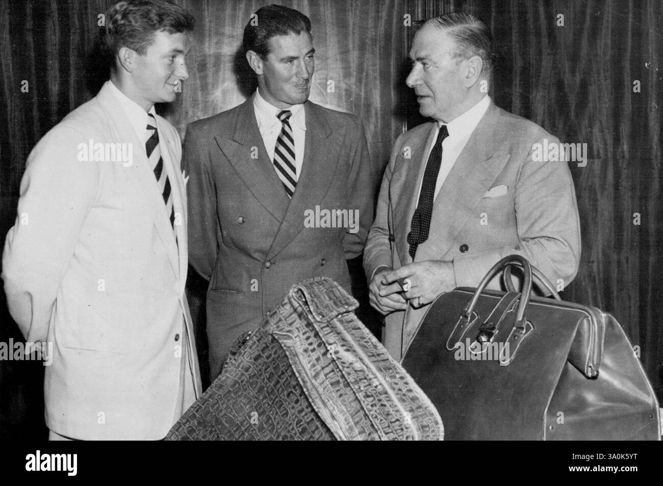 I cricket Richie Benaud (a sinistra) e Keith Miller (al centro) sono stati presentati oggi con borse da viaggio, per conto della Associated Newspapers Ltd. (Editori del Sun), dove entrambi lavorano, dal presidente dei direttori Sir John Butters (a destra). "Potete riportare in vita le ceneri", ha affermato Sir John Butters, che ha salutato i cricket a nome del Consiglio e del personale dell'azienda. Miller e Benaud partono per l'Inghilterra con il team test il 6 marzo. 26 febbraio 1953. Foto Stock