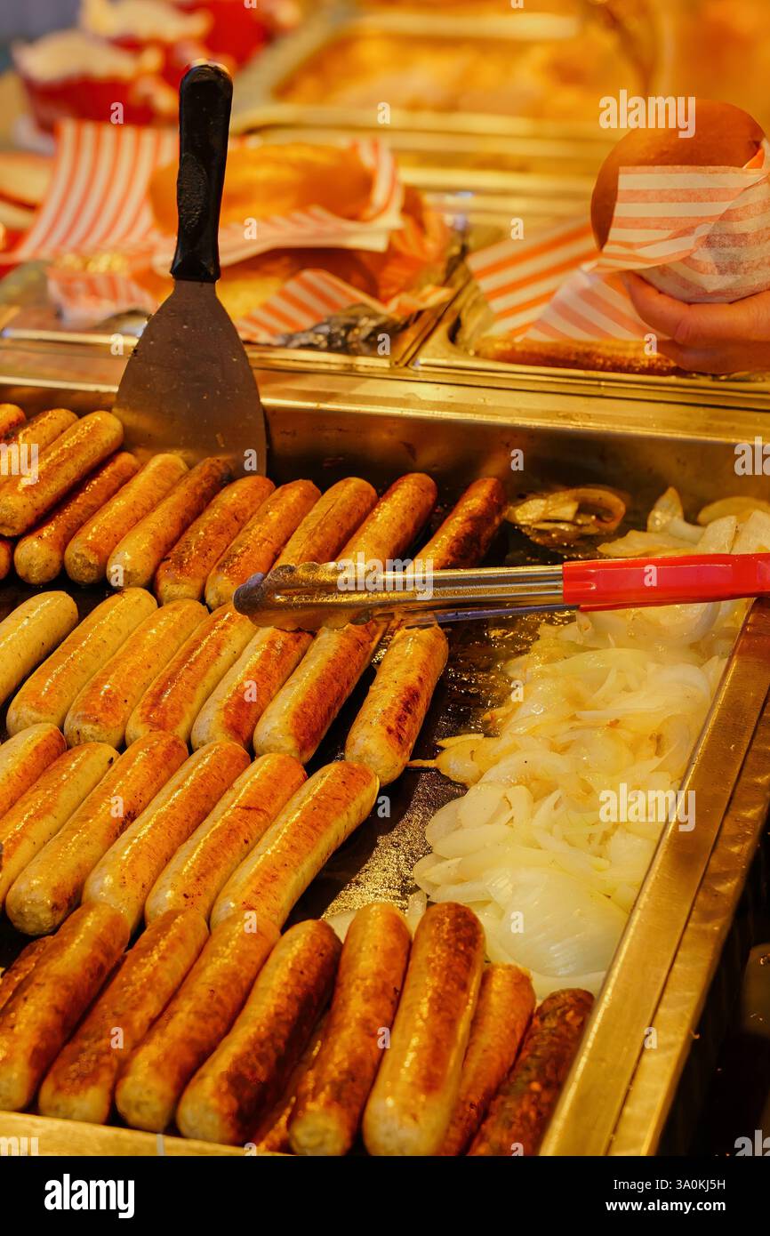 Delizia del cibo di strada: Salsicce dorate, panini morbidi e cipolle pronte per essere gustate. Foto Stock