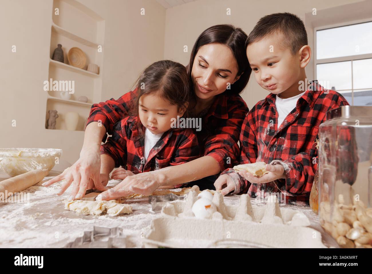 Mamma e bambini felici che cucinano insieme, divertimento per tutta la famiglia in cucina, mani disordinate, legame giocoso, cucina fatta in casa, momenti di gioia dell'infanzia. Foto Stock