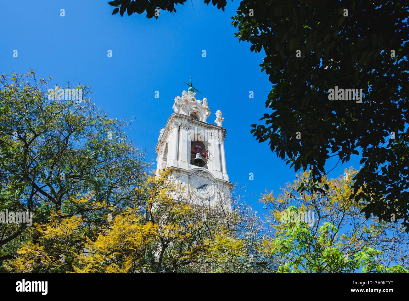 un'alta ed elegante torre bianca dell'orologio con intricati dettagli architettonici, probabilmente parte di una chiesa o di un edificio storico. La campana all'interno della torre è V Foto Stock