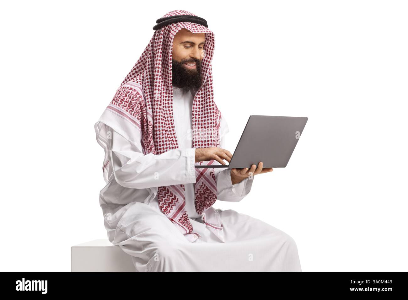 Uomo arabo saudita seduto e che usa un computer portatile isolato su sfondo bianco Foto Stock