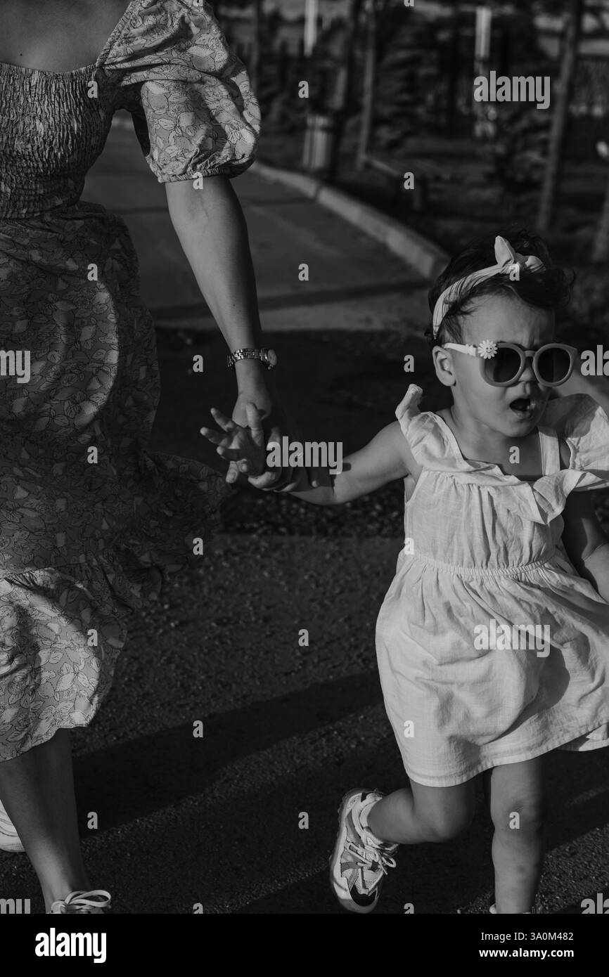 Madre e figlia si godono un gioioso picnic, corrono nel parco, giocano vicino al lago e si divertono in un campo di lavanda. Abiti luminosi, estate Foto Stock