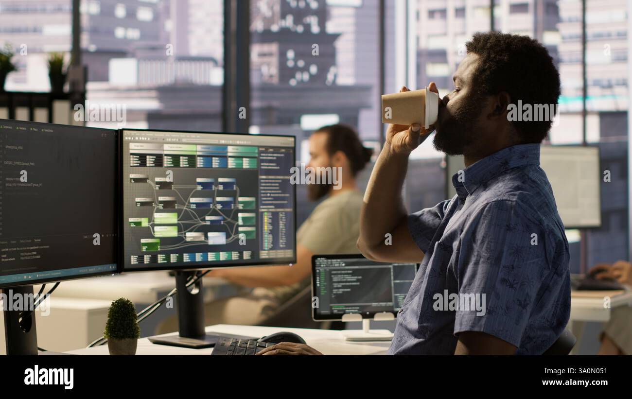 L'amministratore di sistema in ufficio sbadiglia durante il turno, si sente stanco mentre guarda l'interfaccia software sul PC. Uomo esausto, assonnato nello spazio di lavoro, programmazione sul monitor del computer, telecamera A. Foto Stock