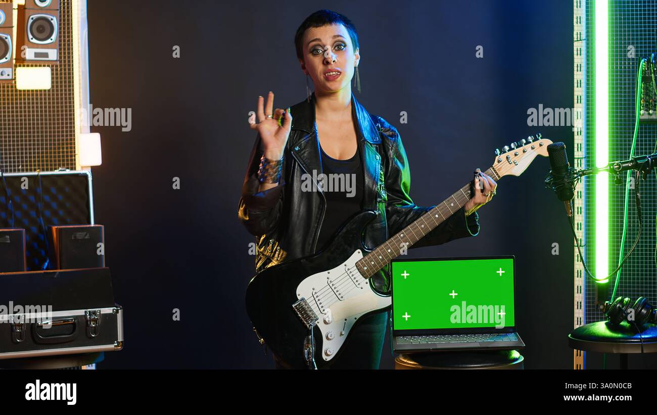 La rock star ribelle e cool esegue un'esibizione dal vivo accanto ai tasti Chroma del nightclub, sentendosi potente nella sua giacca in pelle e nel trucco scuro. Cantante potente e alla moda che si esibisce. Telecamera A.. Foto Stock