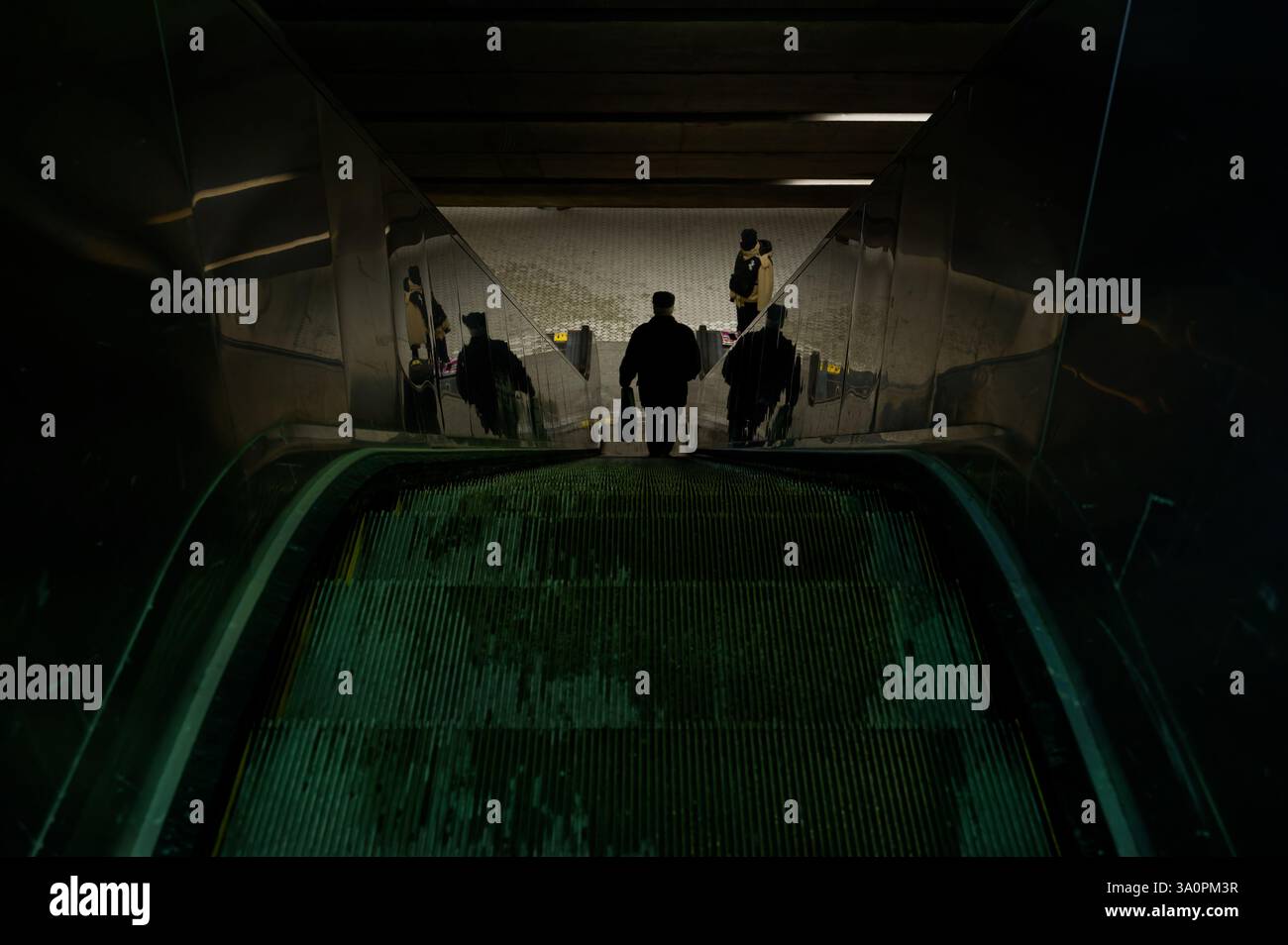 Una figura oscura scende su una scala mobile nel sottosuolo di Montreal. Foto Stock
