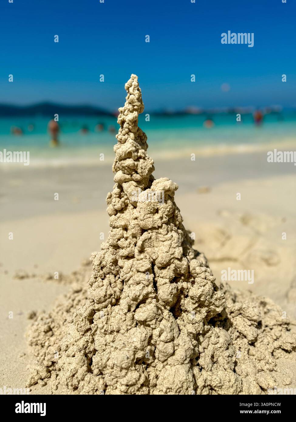 Castello di sabbia artistico su una Sunny Beach Un castello di sabbia scolpito naturalmente sorge dalla spiaggia baciata dal sole, mostrando la sua struttura intricata e organica. - Immagine stock catturata con smartphone