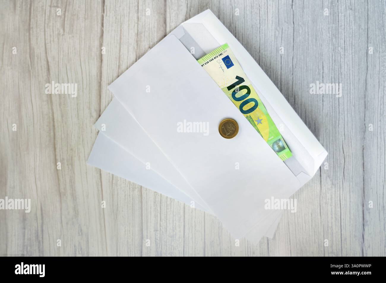Banconota da 100 euro in busta e una moneta da 1 euro su di essa Foto Stock