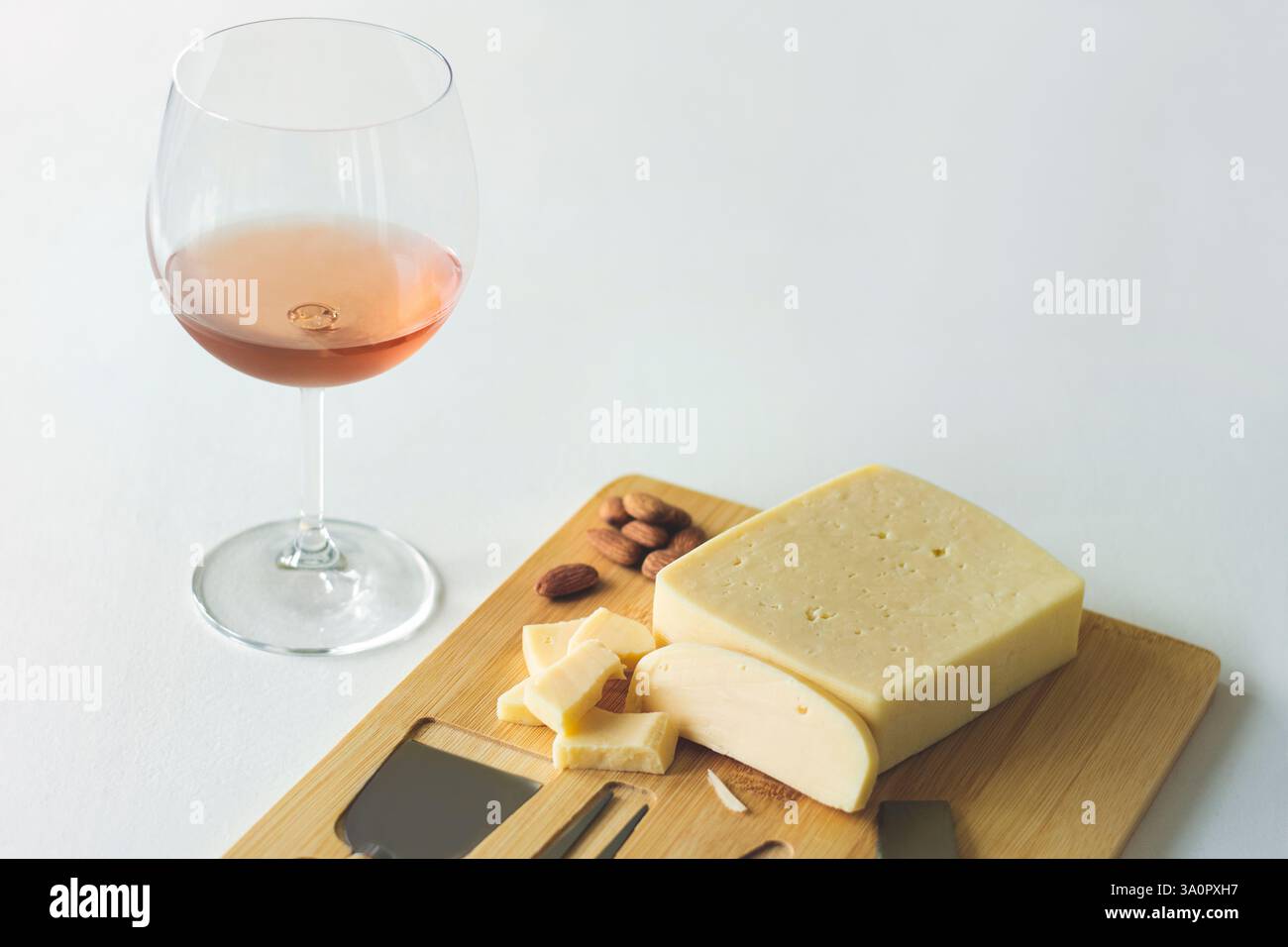 Vino d'arancia fruttato con formaggio e mandorle su un tagliere di legno, degustazione di formaggi e vini Foto Stock