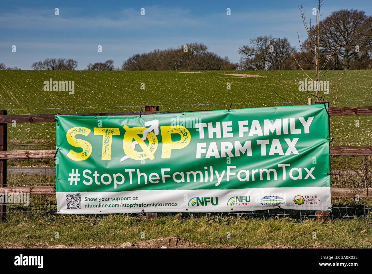 FERMA IL banner FISCALE DELL'AZIENDA AGRICOLA DI FAMIGLIA attaccato a una recinzione di legno con un campo coltivabile piantato sullo sfondo Foto Stock