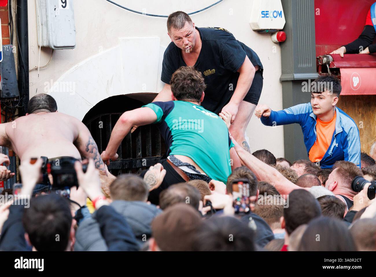 Atherstone Ball Game 2025. Nella foto, gli ultimi minuti di Long Street e i festeggiamenti alla fine del gioco della palla. L'Atherstone Ball Game è una partita di "calcio medievale" giocata ogni anno il martedì grasso nella città inglese di Atherstone, Warwickshire. La partita onora una partita giocata tra Leicestershire e Warwickshire nel 1199, quando le squadre gareggiarono per una borsa d'oro, e che fu vinta dal Warwickshire. Un tempo eventi simili si tennero in molte città in tutta l'Inghilterra, ma quello di Atherstone è ora uno di almeno tre di questi giochi che vengono ancora giocati ogni anno a Shrovetide. Foto Stock