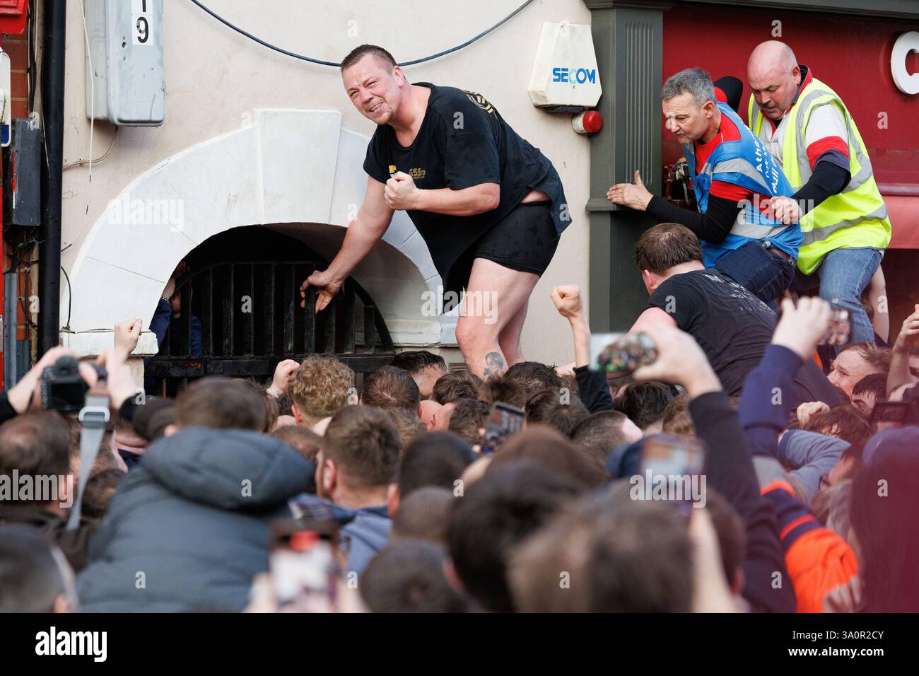 Atherstone Ball Game 2025. Nella foto, gli ultimi minuti di Long Street e i festeggiamenti alla fine del gioco della palla. L'Atherstone Ball Game è una partita di "calcio medievale" giocata ogni anno il martedì grasso nella città inglese di Atherstone, Warwickshire. La partita onora una partita giocata tra Leicestershire e Warwickshire nel 1199, quando le squadre gareggiarono per una borsa d'oro, e che fu vinta dal Warwickshire. Un tempo eventi simili si tennero in molte città in tutta l'Inghilterra, ma quello di Atherstone è ora uno di almeno tre di questi giochi che vengono ancora giocati ogni anno a Shrovetide. Foto Stock