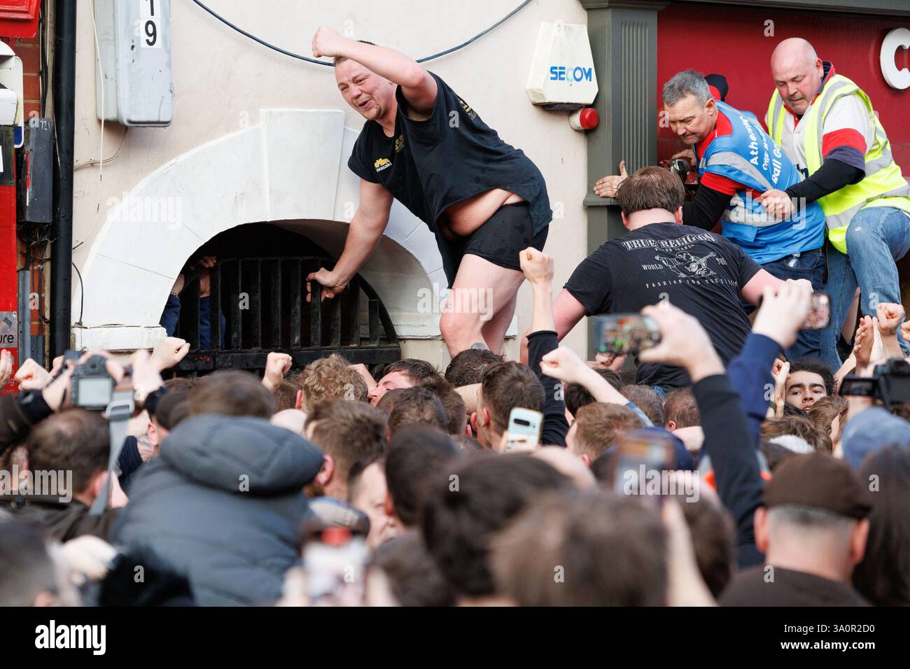 Atherstone Ball Game 2025. Nella foto, gli ultimi minuti di Long Street e i festeggiamenti alla fine del gioco della palla. L'Atherstone Ball Game è una partita di "calcio medievale" giocata ogni anno il martedì grasso nella città inglese di Atherstone, Warwickshire. La partita onora una partita giocata tra Leicestershire e Warwickshire nel 1199, quando le squadre gareggiarono per una borsa d'oro, e che fu vinta dal Warwickshire. Un tempo eventi simili si tennero in molte città in tutta l'Inghilterra, ma quello di Atherstone è ora uno di almeno tre di questi giochi che vengono ancora giocati ogni anno a Shrovetide. Foto Stock