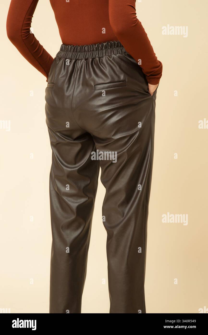 Fotografia in studio di una giovane modella donna che indossa pantaloni marrone in ecopelle con tacco alto Foto Stock