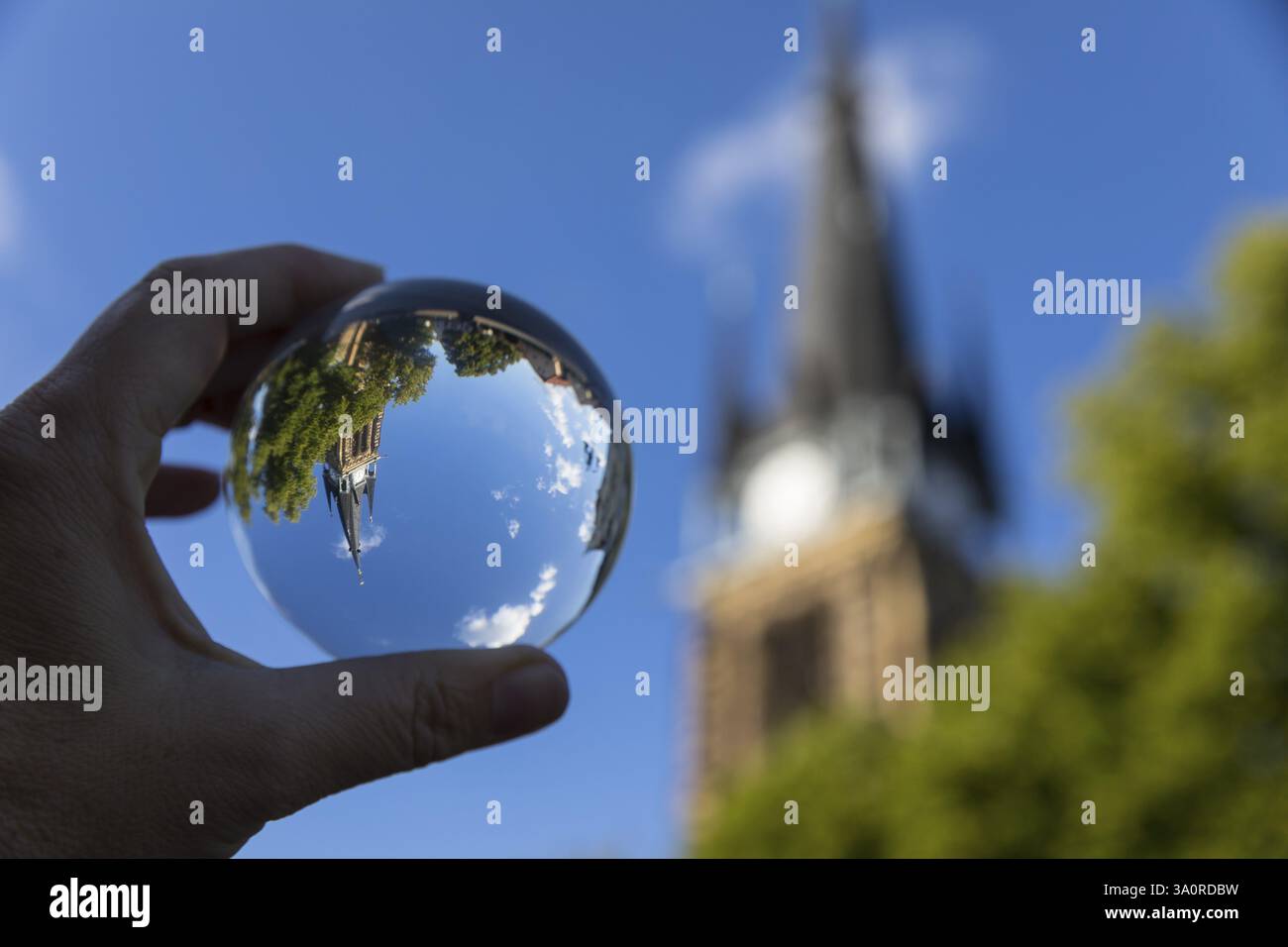 Mano con sfera di vetro in cui si riflettono il campanile della chiesa di San Martino e la locanda centrale, Weinboehla, Sassonia, Germania, Europa Foto Stock