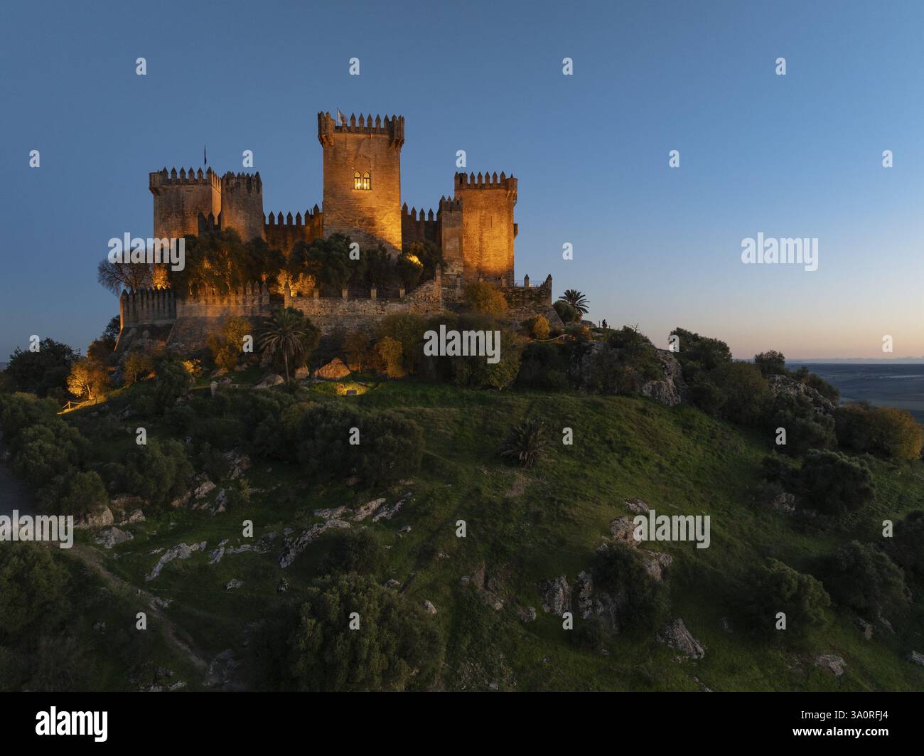 L'imponente castello moresco di Almodovar del Rio, risalente all'VIII secolo, si erge sopra la valle del fiume Guadalquivir. Illuminato al crepuscolo. Colpo di drone. Cai¿½ Foto Stock