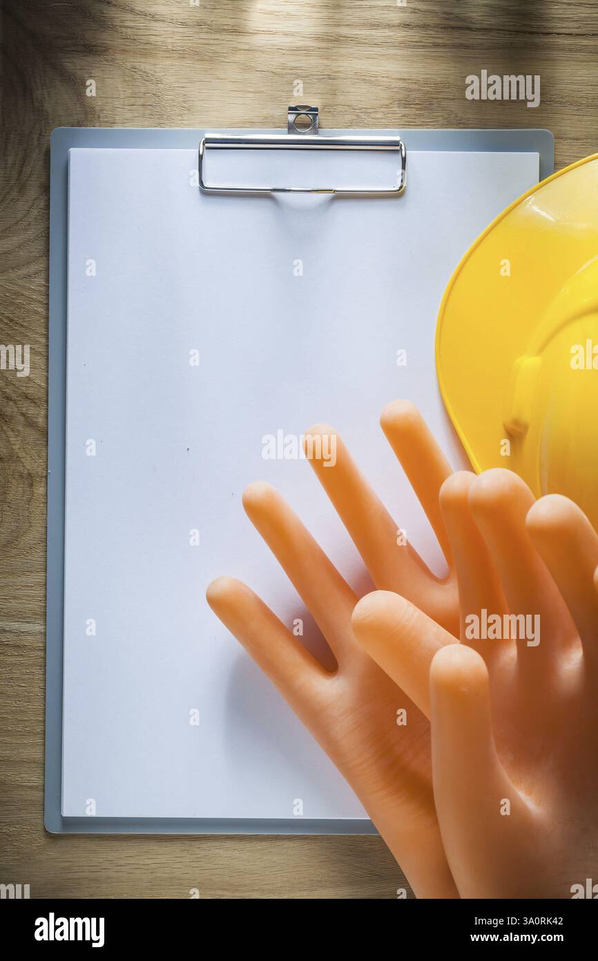 Guanti dielettrici in carta per appunti casco da costruzione su tavola di legno Foto Stock