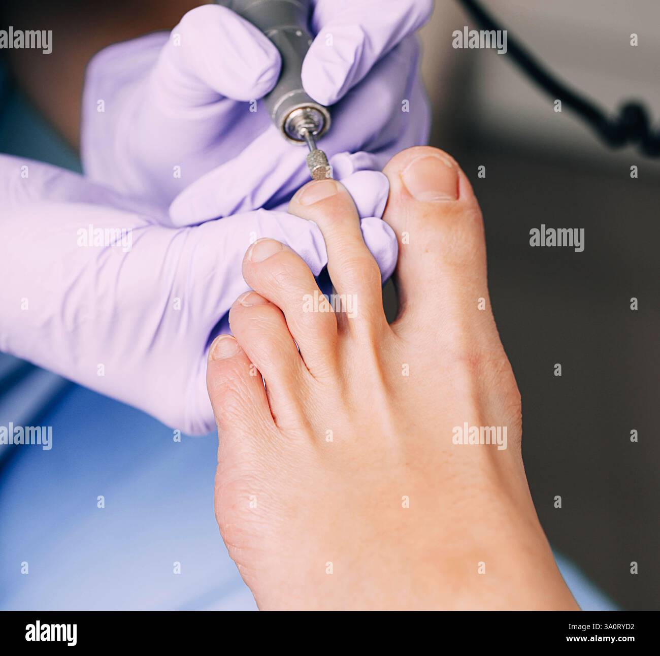 Un cosmetologo fornisce assistenza dettagliata per le unghie del piede utilizzando strumenti specializzati durante una sessione di trattamento del piede in un ambiente clinico. Foto Stock