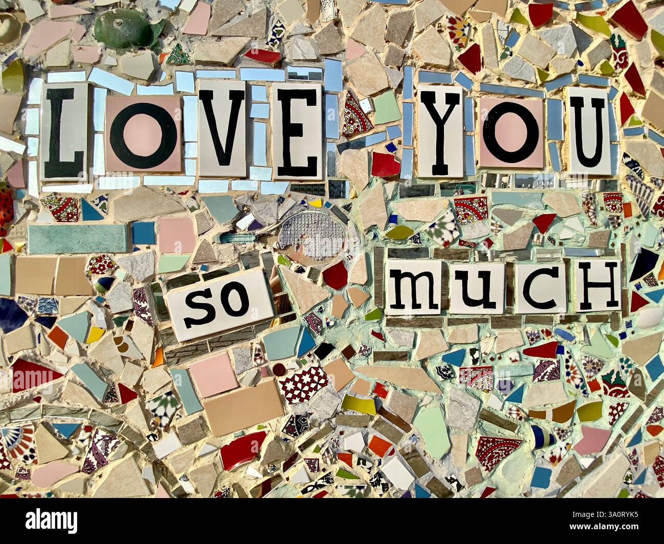 Primo piano di un mosaico splendidamente realizzato con le parole "TI AMO COSÌ TANTO". Il mosaico è composto da varie piccole piastrelle colorate Foto Stock